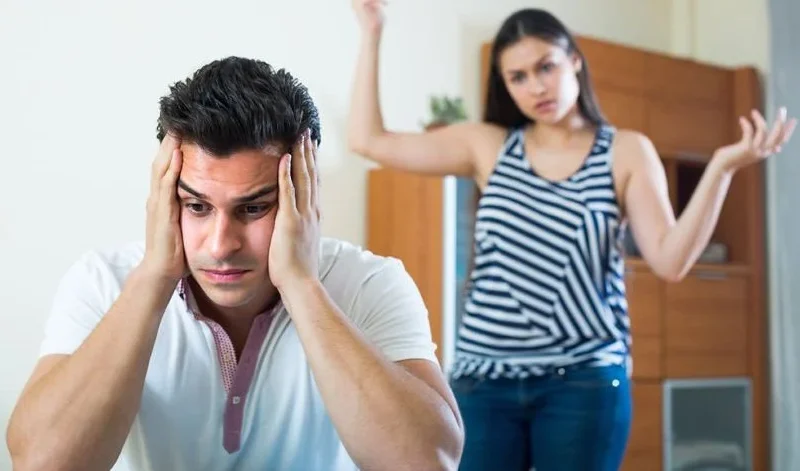 Homem sobrecarregado emocionalmente e mulher discutindo ao fundo — imagem usada pelo psicólogo Elídio Almeida em post sobre floodlighting e terapia de casal.
