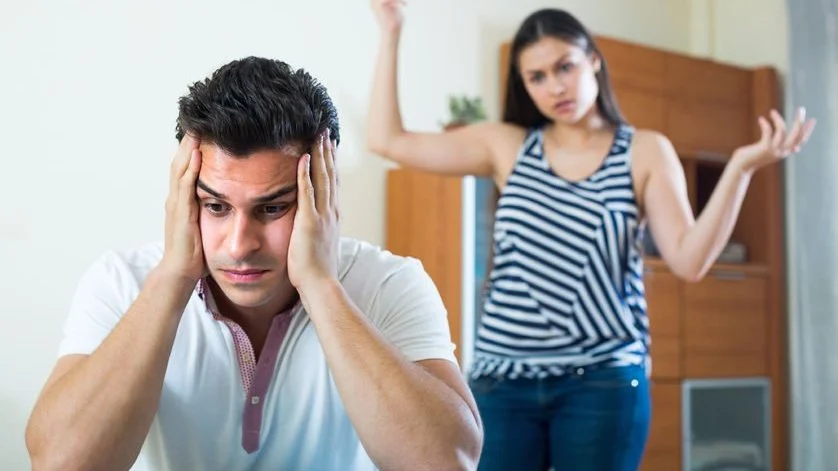 Homem sobrecarregado emocionalmente e mulher discutindo ao fundo — imagem usada pelo psicólogo Elídio Almeida em post sobre floodlighting e terapia de casal.